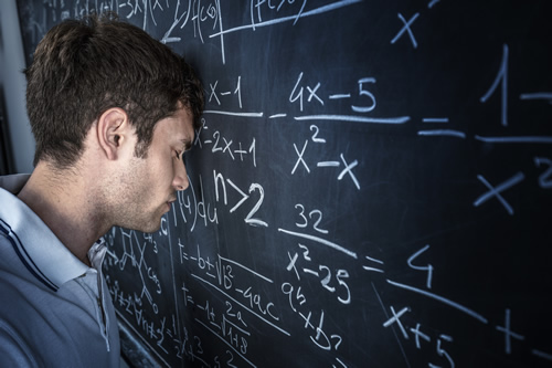 A student leans his head against a math chalkboard in frustration due to low STEM engagement.