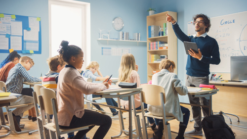 Enthusiastic Teacher Giving a Lesson in Elementary School to Cla ...